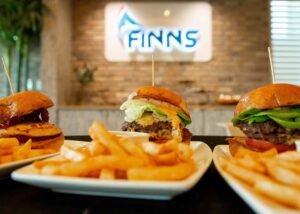 Plates of sliders and fries in front of the Finns Restaurant sign